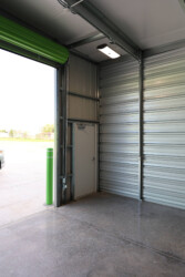 view from inside drive-up storage facility with a regular door entrance closed with garage/roll up door open